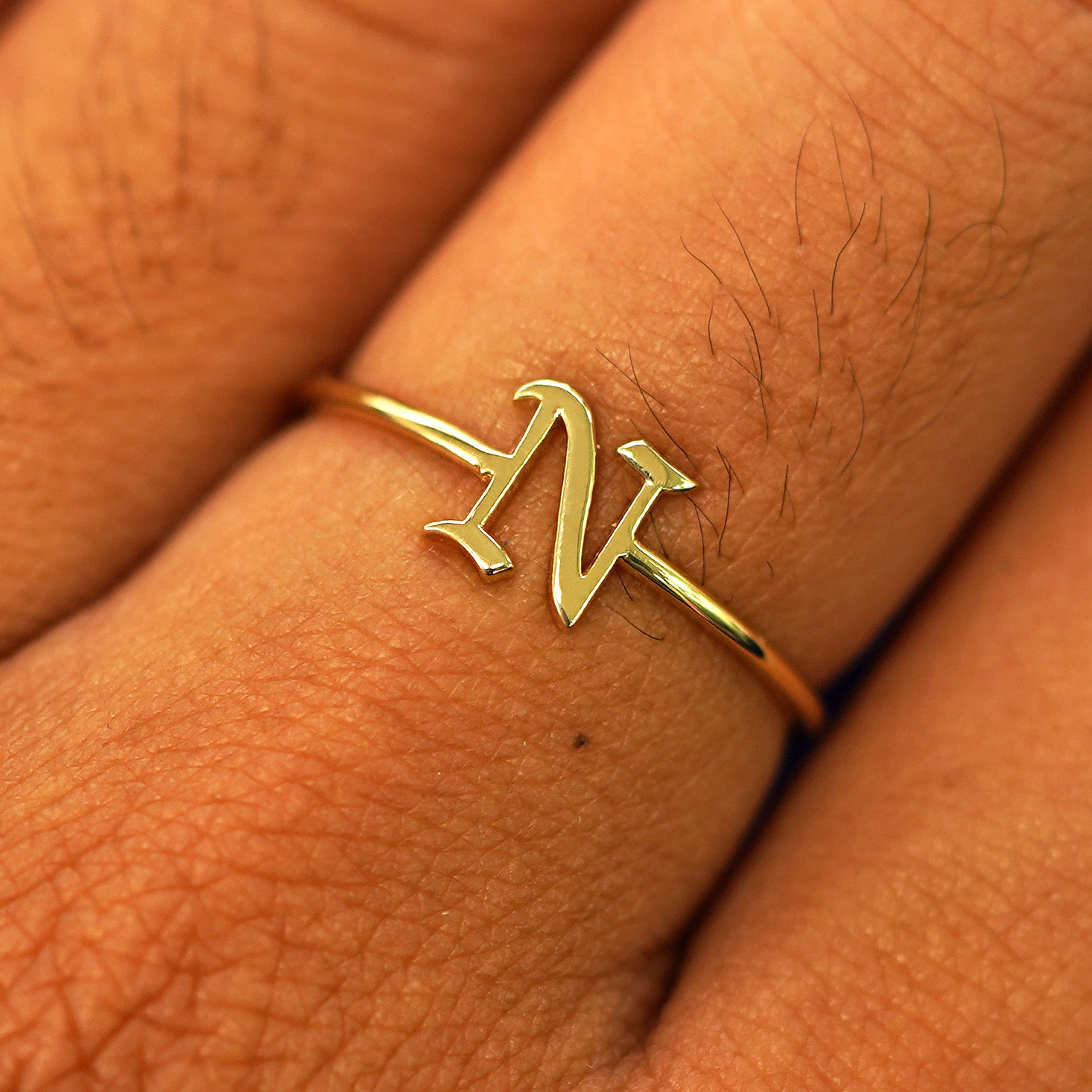 Close up view of a model's fingers wearing a 14k yellow gold Initial Ring with the letter N