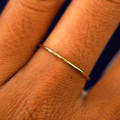 Close up view of a model's hand wearing a solid gold Line Ring