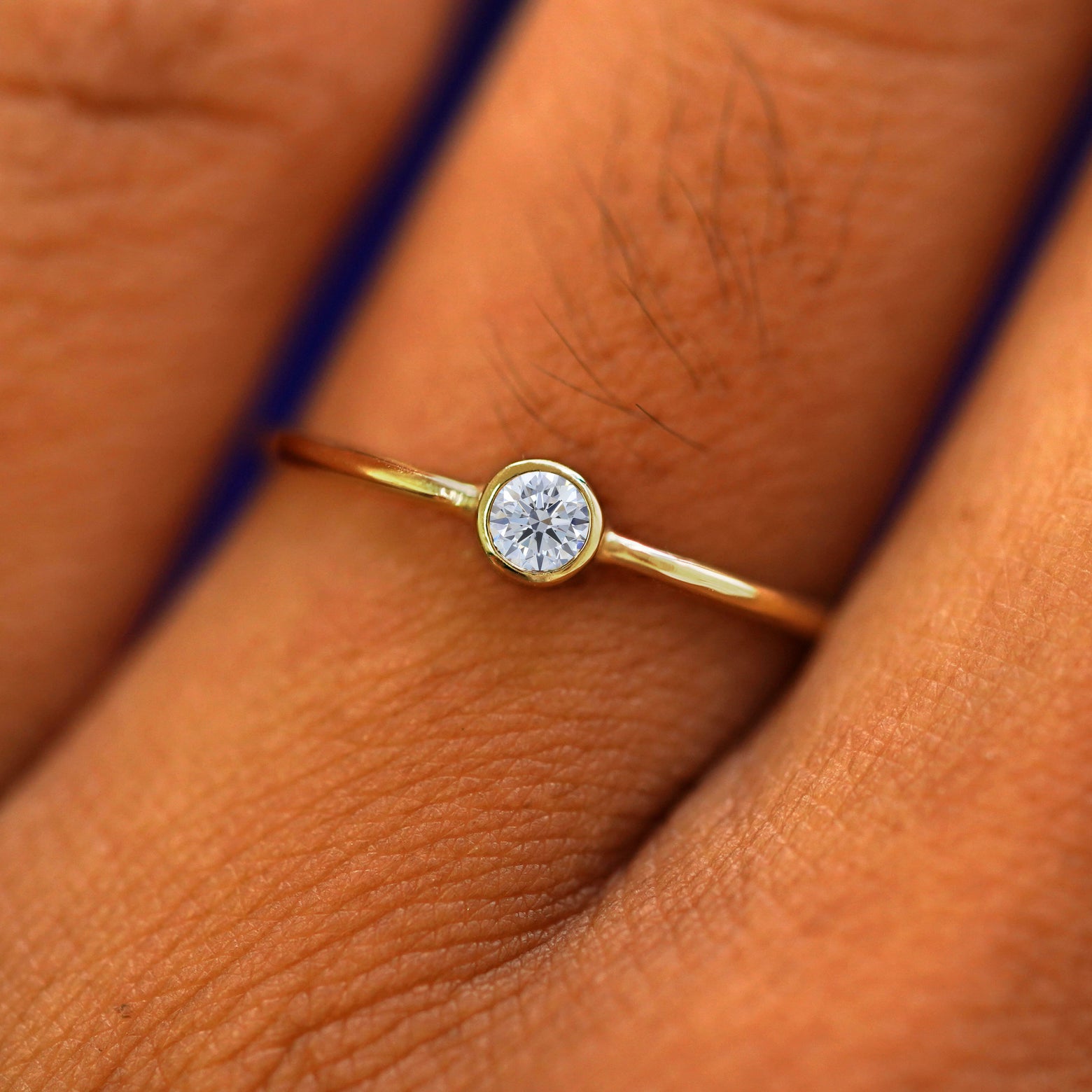 Close up view of a model's fingers wearing a 14k yellow gold Moissanite Ring