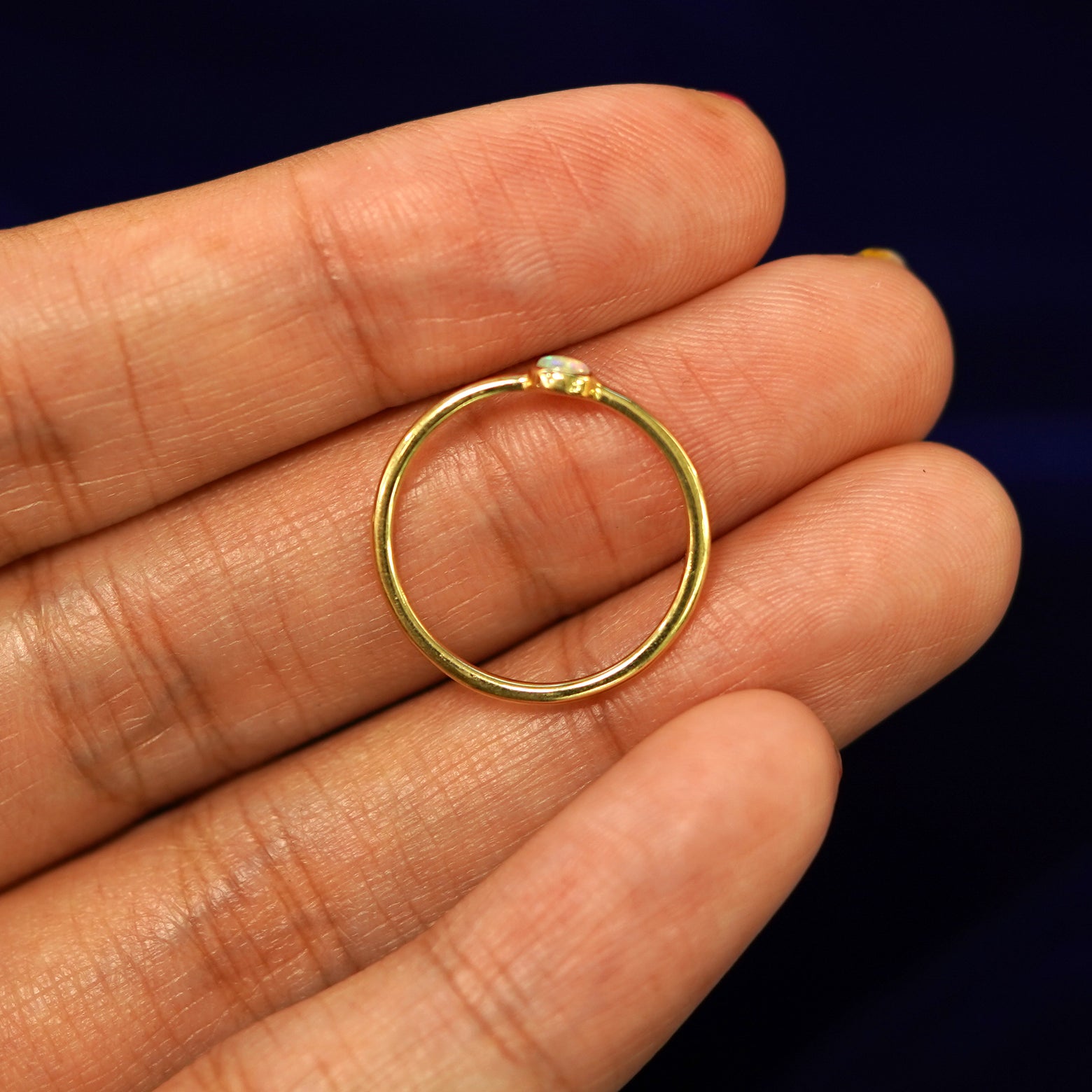 A 14k yellow gold Opal Ring laying in on a models fingers to show the thickness of the band
