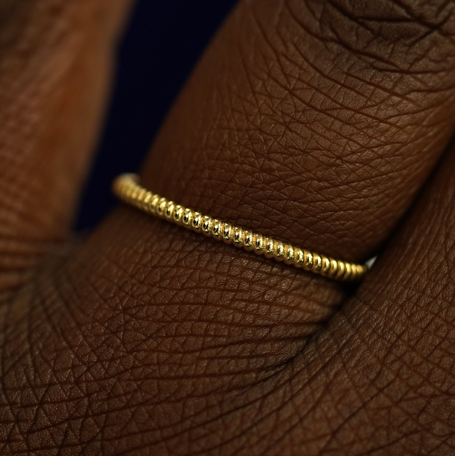 Close up view of a model's fingers wearing a 14k yellow gold Rope Ring