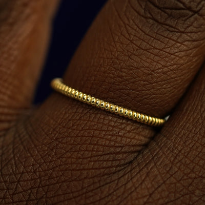 Close up view of a model's fingers wearing a 14k yellow gold Rope Ring