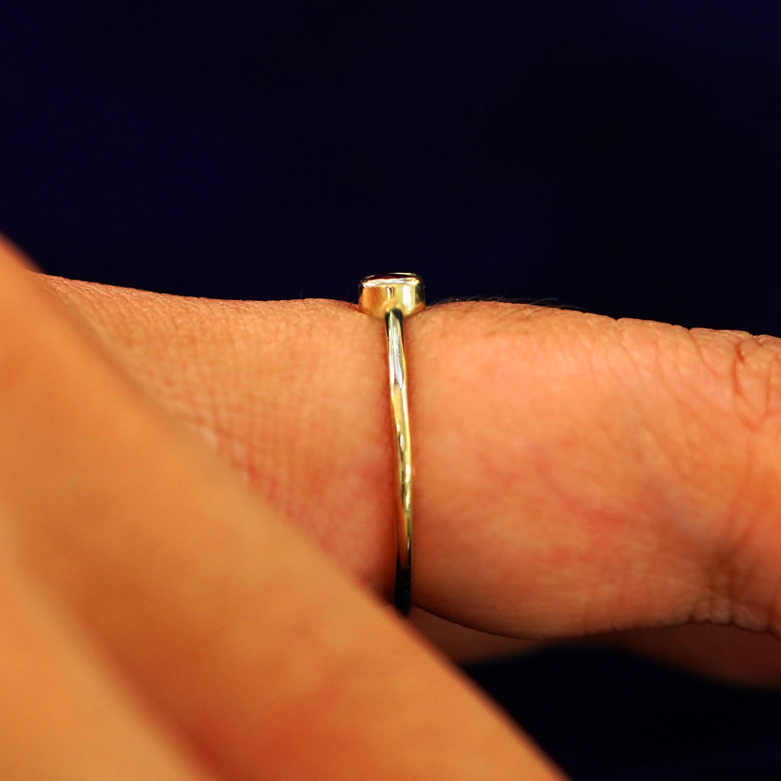 Side view of a model's finger wearing a yellow gold Ruby Ring