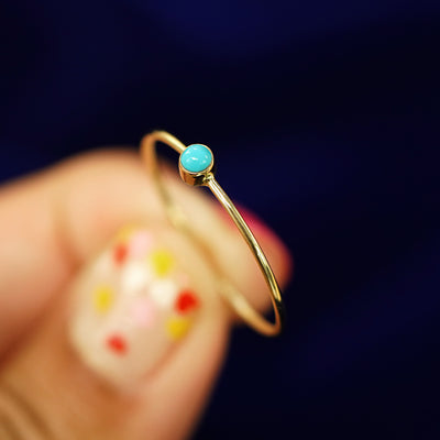 A model holding a Turquoise Ring tilted to show the bezel setting