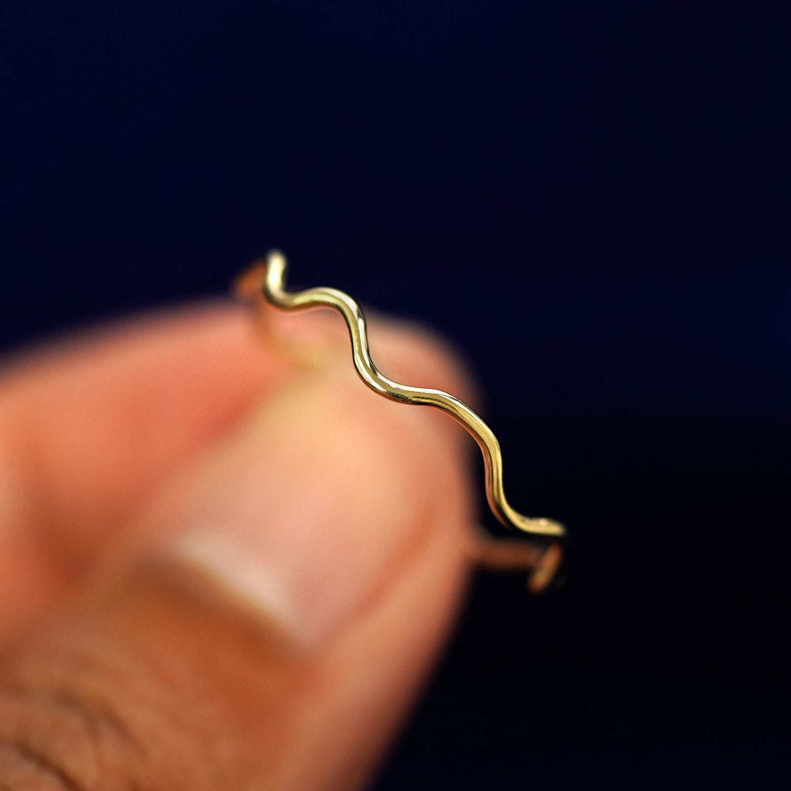 A model holding a Wave Ring tilted to show the side of the ring