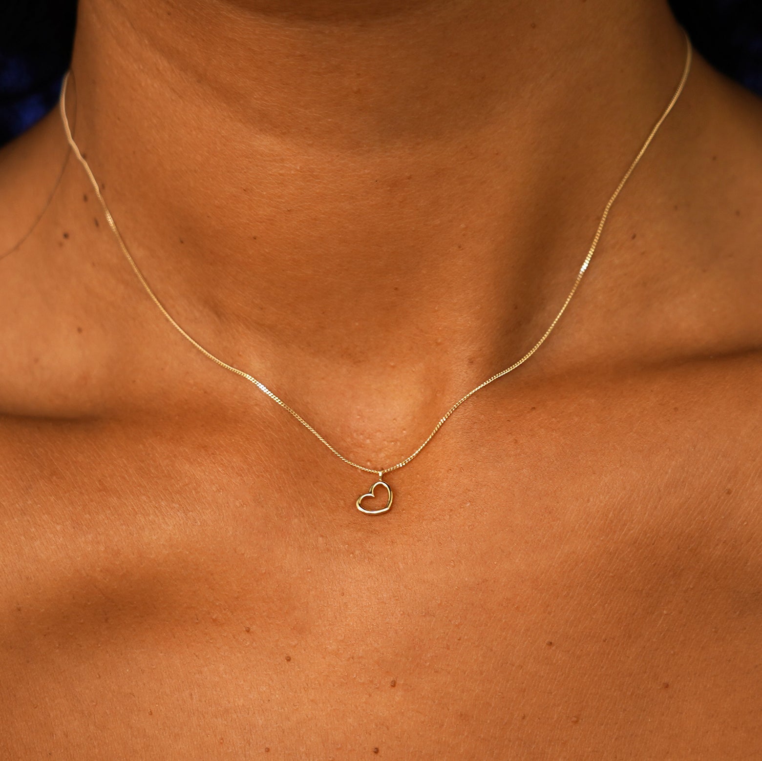 Close up view of a model's neck wearing a solid yellow gold Heart Necklace