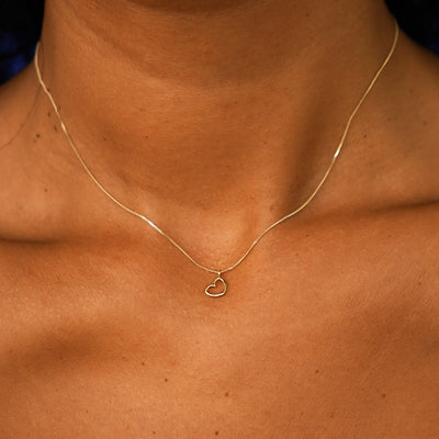 Close up view of a model's neck wearing a solid yellow gold Heart Necklace