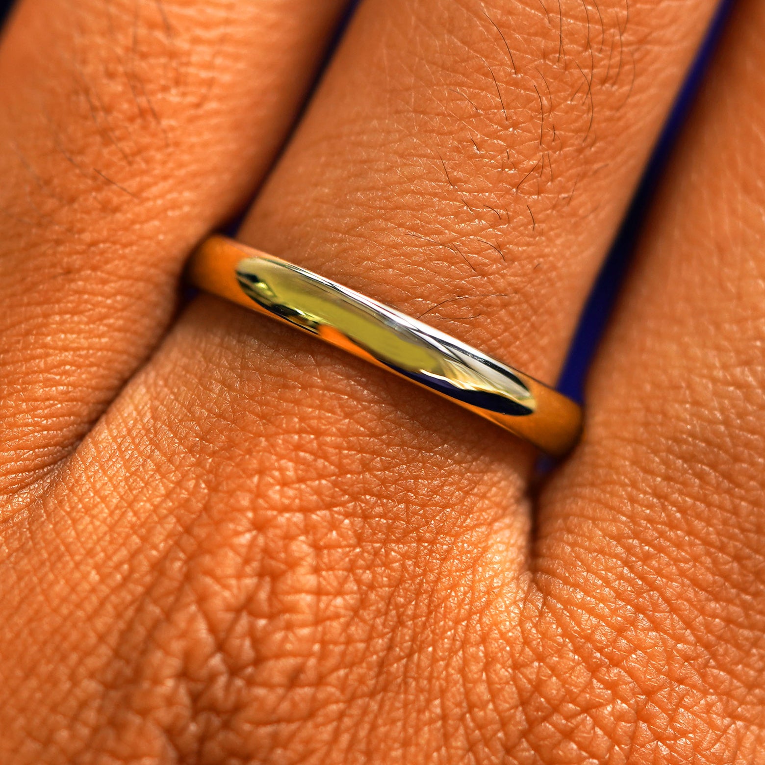 Close up view of a model's fingers wearing a 14k yellow gold Curvy Mirror Band