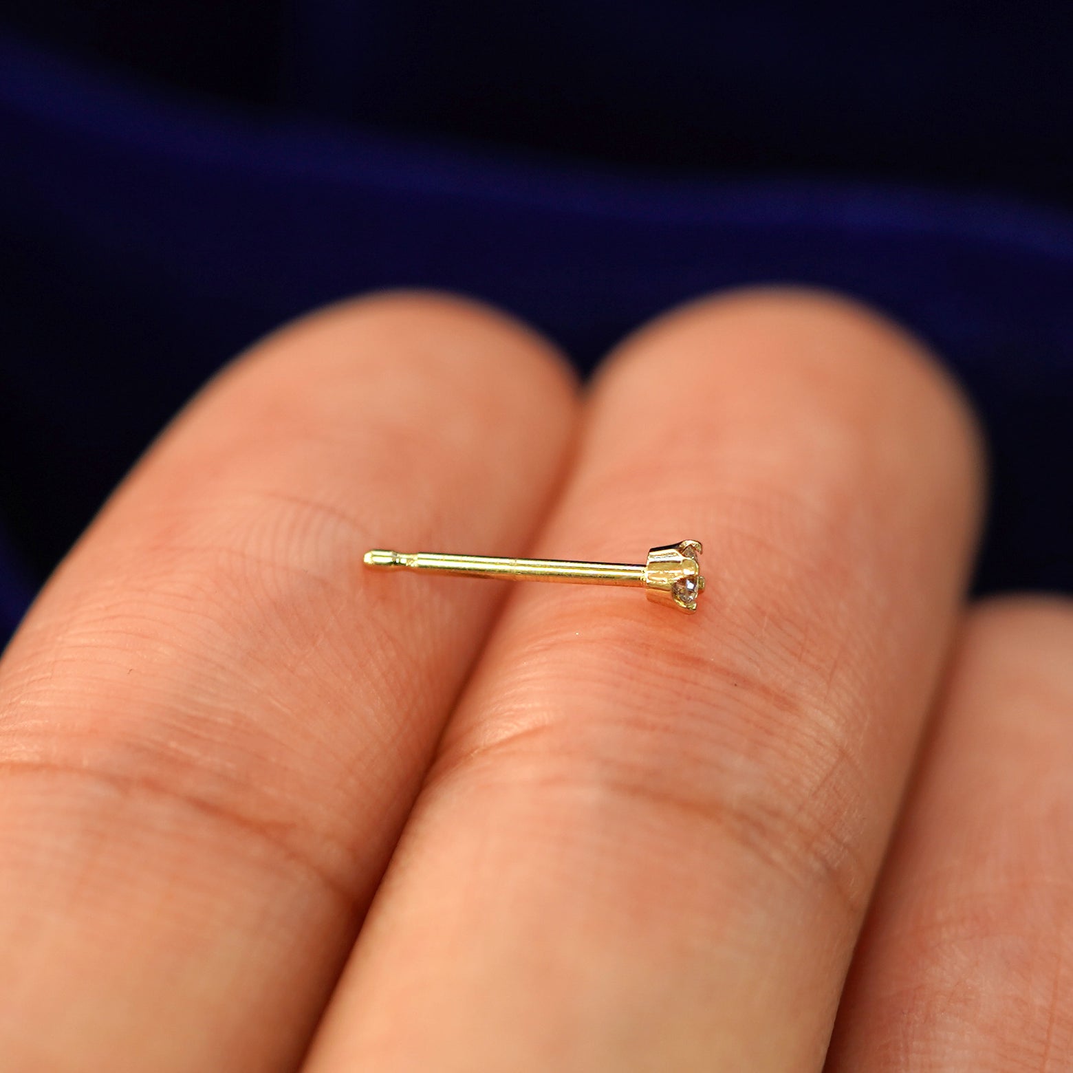 Side view of a yellow gold 2mm Diamond Earrings shown with pushback posts and no backings resting on a models fingertip