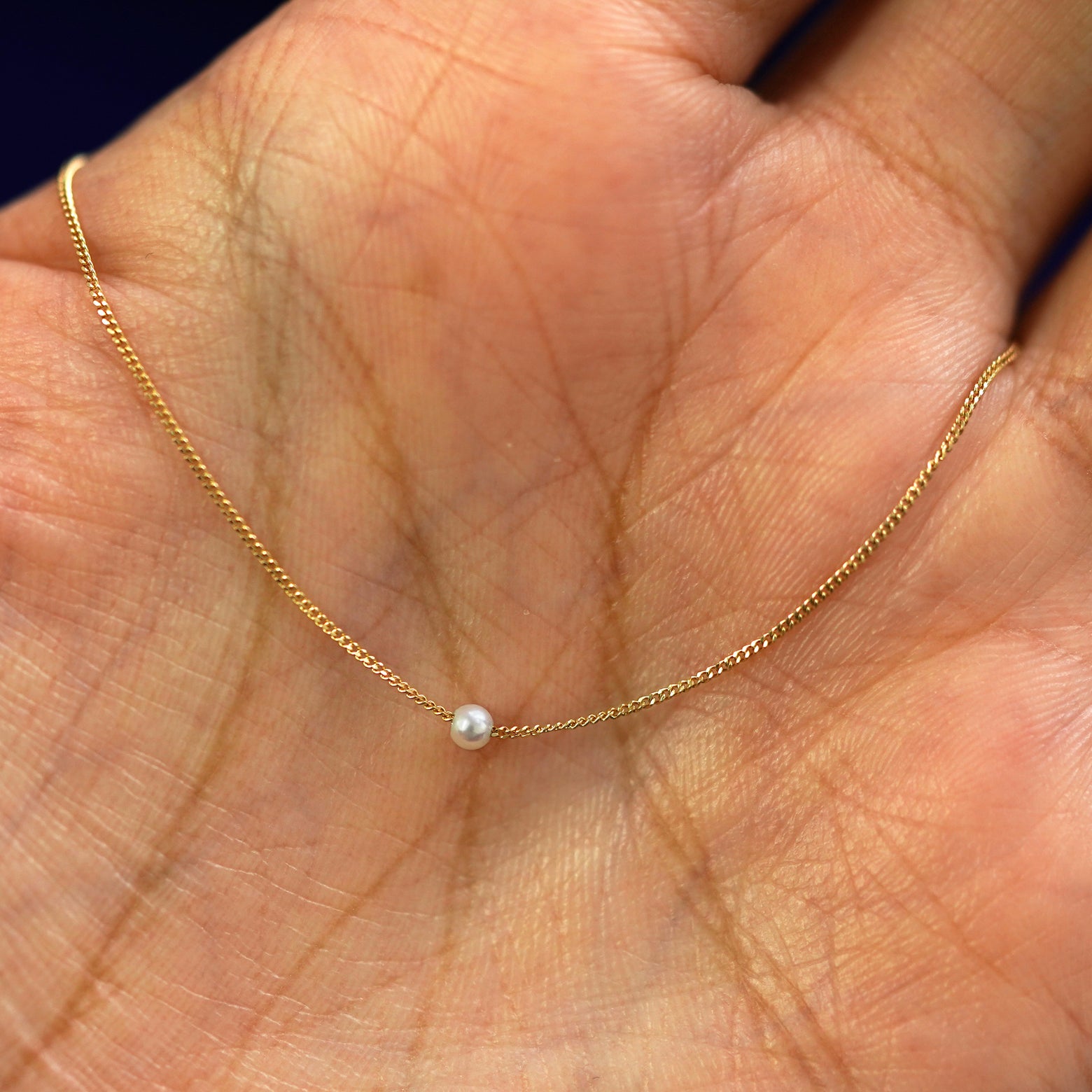 A 2mm pearl slide bracelet draped on a model's palm