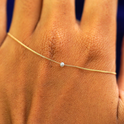 A 2mm pearl slide bracelet resting on the back of a model's hand