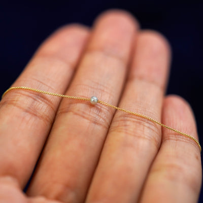A 2mm pearl slide bracelet resting on a model's fingers