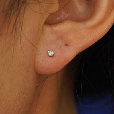 Close up view of a model's ear wearing a solid 14k yellow gold 2mm Diamond Earring