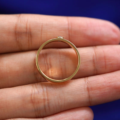 A yellow gold sapphire Gemstone Industrial Band in a model's hand showing the thickness of the band