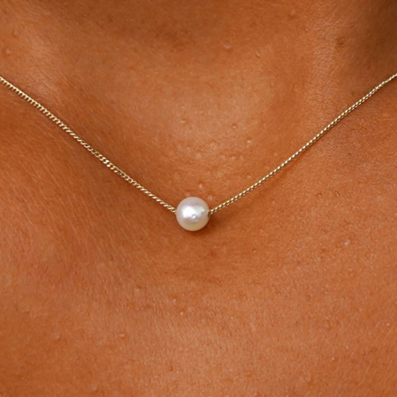 Close up view of a model's neck wearing a yellow gold Pearl Slide Necklace with a 4mm pearl