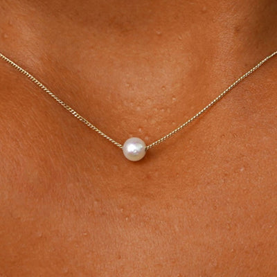 Close up view of a model's neck wearing a yellow gold Pearl Slide Necklace with a 4mm pearl