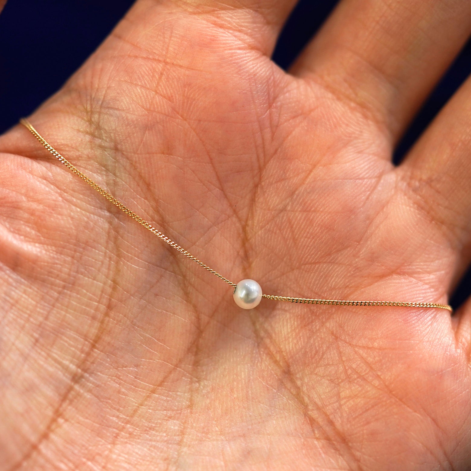 A 4mm pearl slide necklace draped on a model's palm