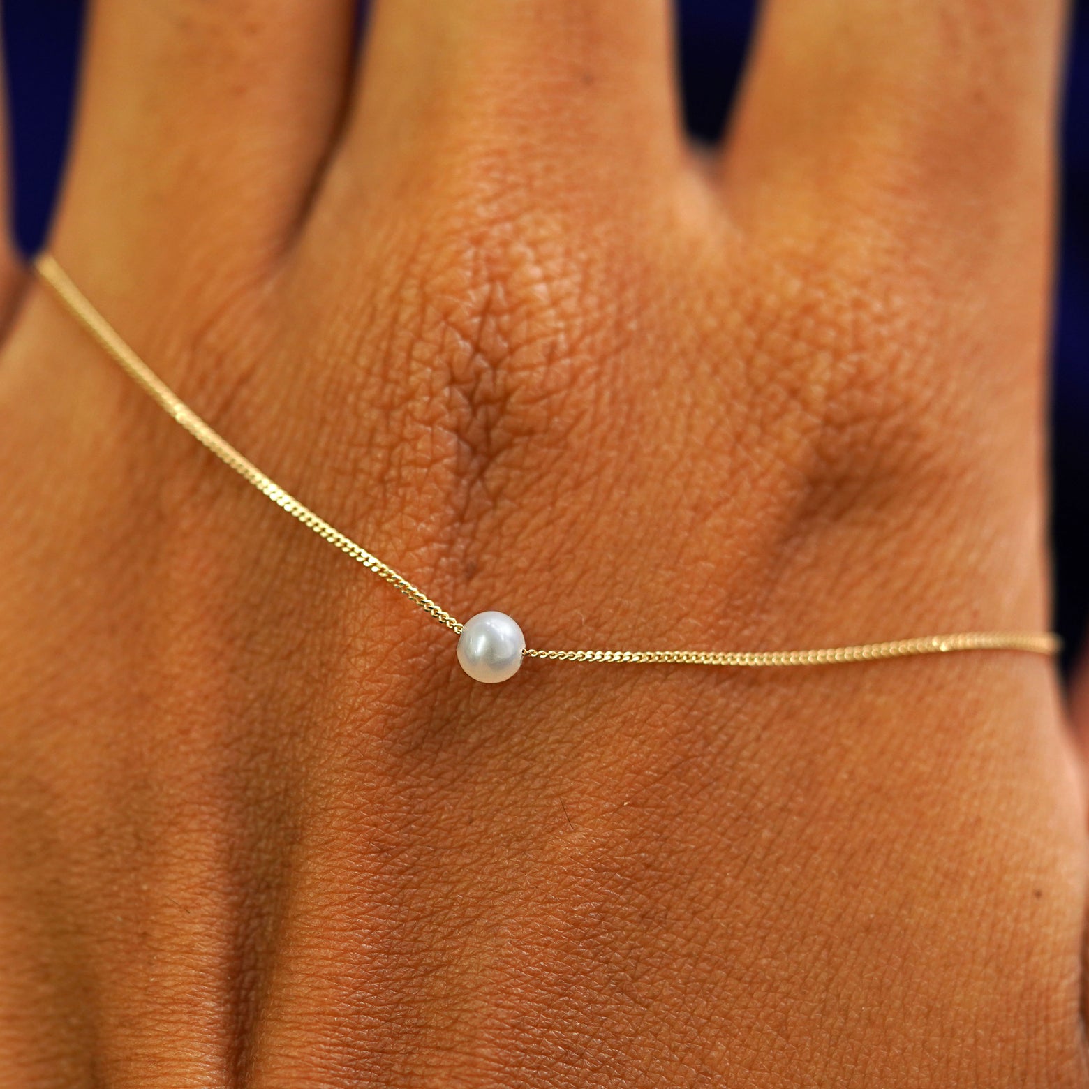 A 4mm pearl slide necklace resting on the back of a model's hand