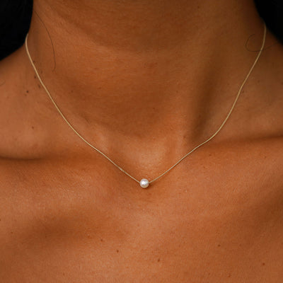 A model's neck wearing a yellow gold Pearl Slide Necklace with a 4mm pearl