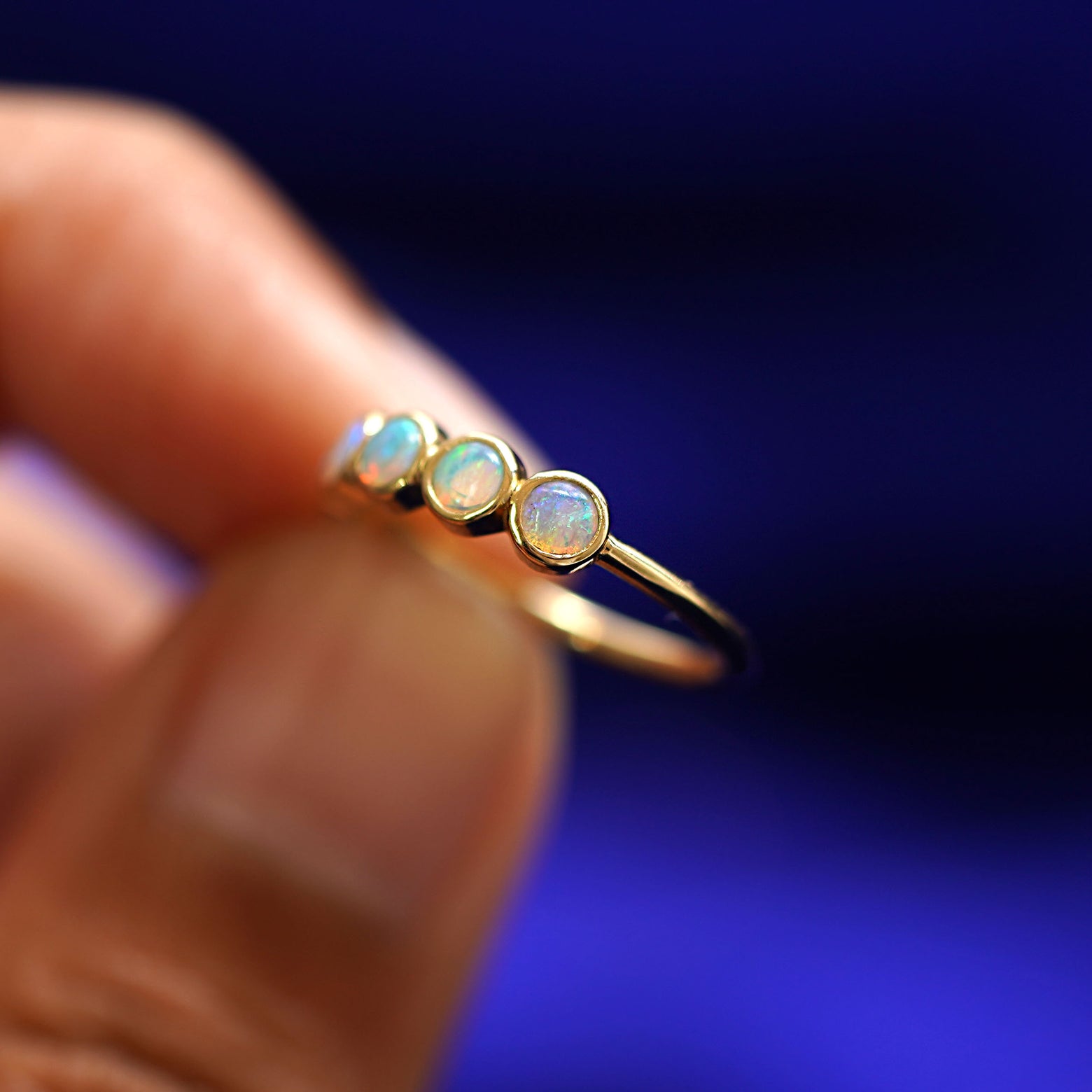 A hand holding a 5 Opals Ring to show the side view