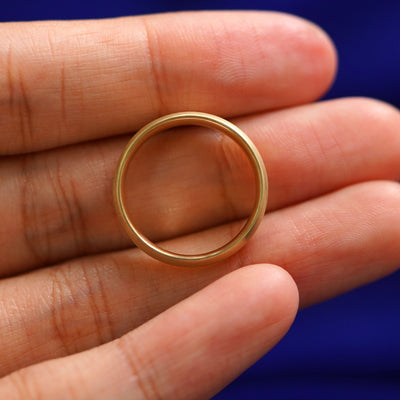 A yellow gold Curvy Matte Band in a model's hand showing the thickness of the band