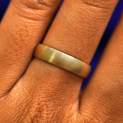 Close up view of a model's fingers wearing a 14k yellow gold Curvy Matte Band