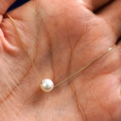 A 6mm pearl slide necklace draped on a model's palm