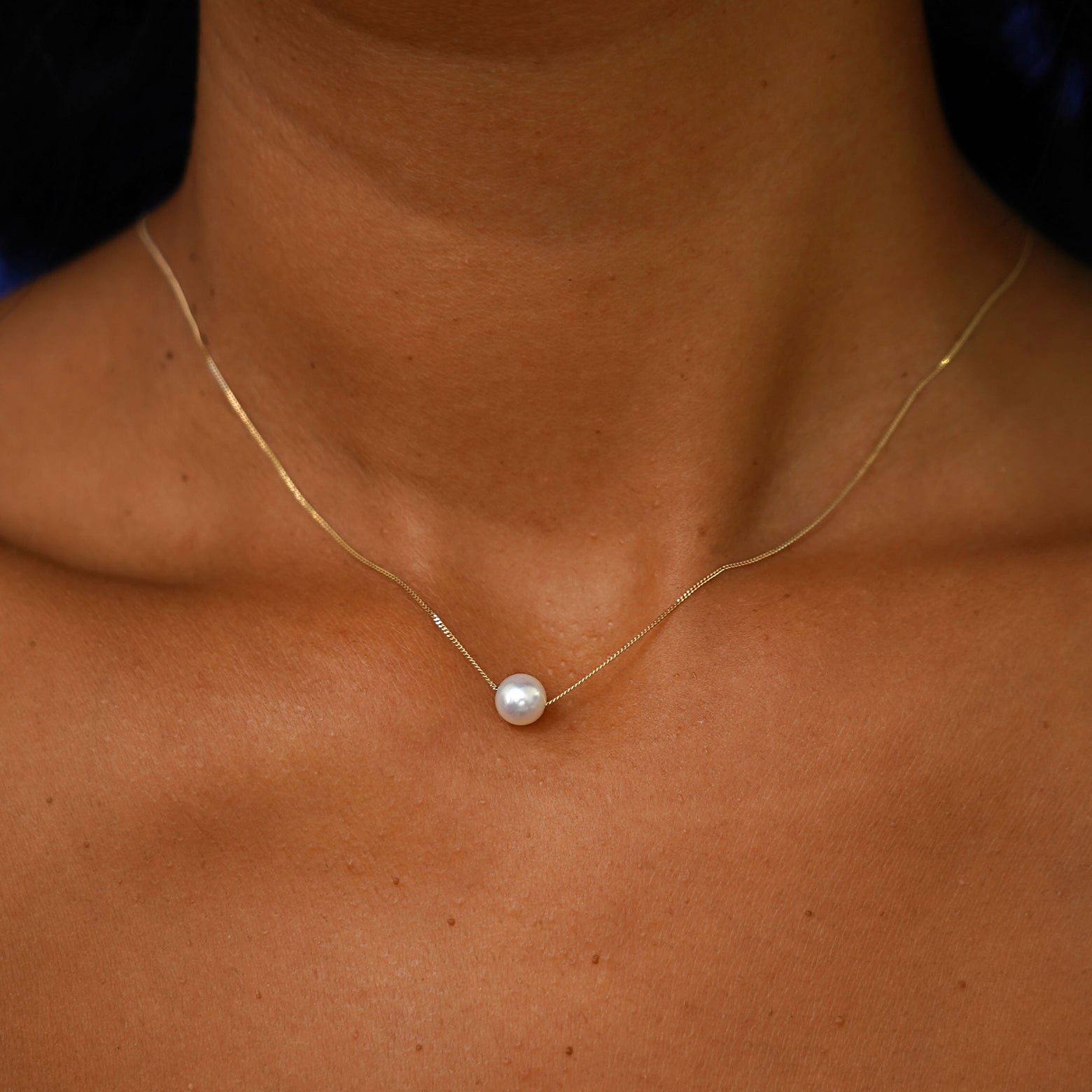 A model's neck wearing a yellow gold Pearl Slide Necklace with a 6mm pearl