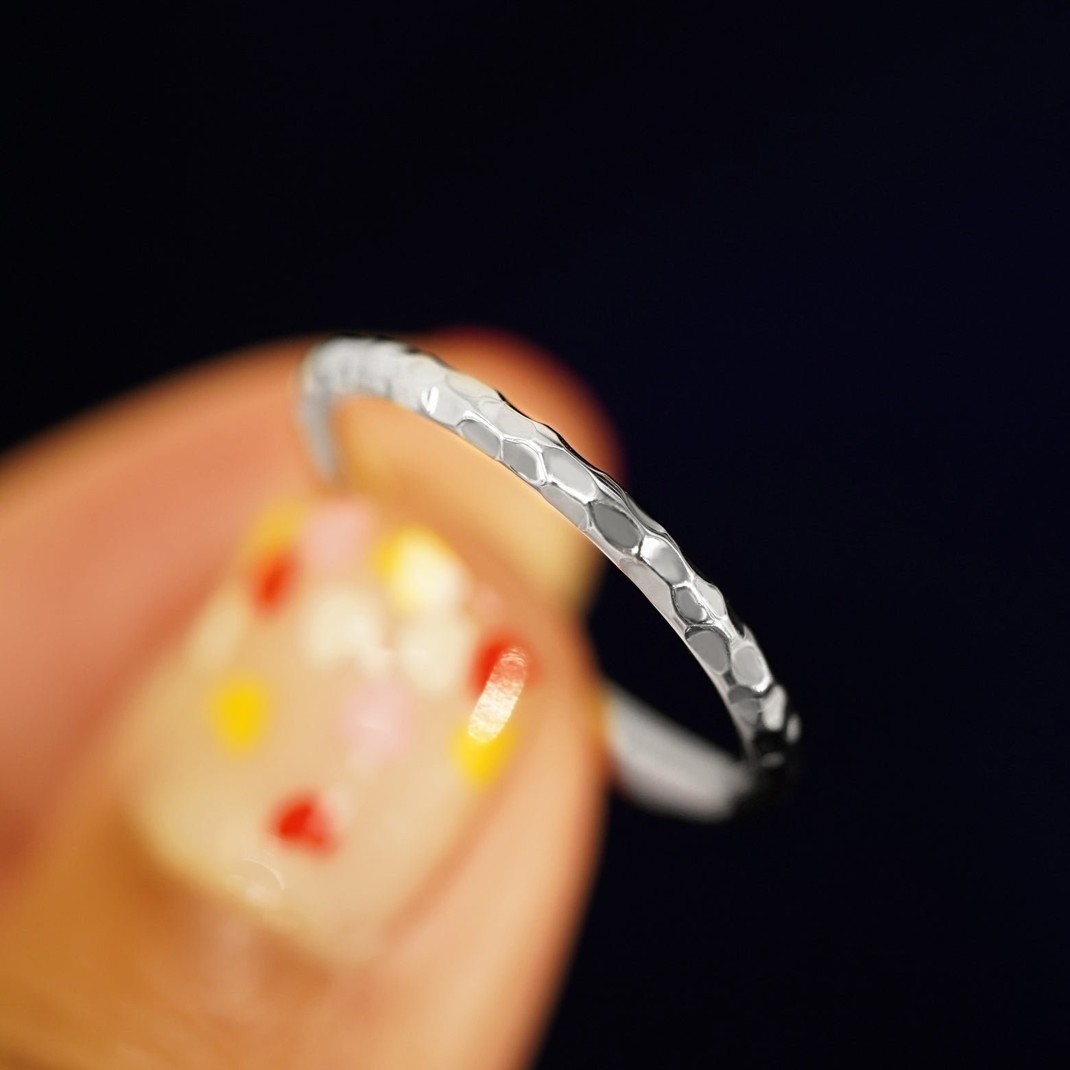 A model holding a Platinum Curvy Hammered Band tilted to show the details of the hammered finish