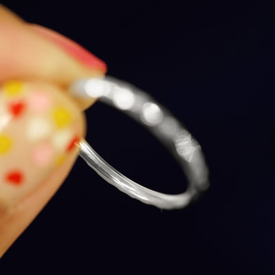 A model holding a Platinum Curvy Hammered Band tilted to show the inside of the band