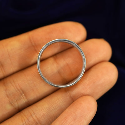 A Platinum Industrial Mirror Band resting on a model's fingers to show the thickness of the band