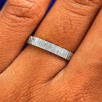 Close up view of a model's fingers wearing a 2mm 950 platinum Industrial Wood Band