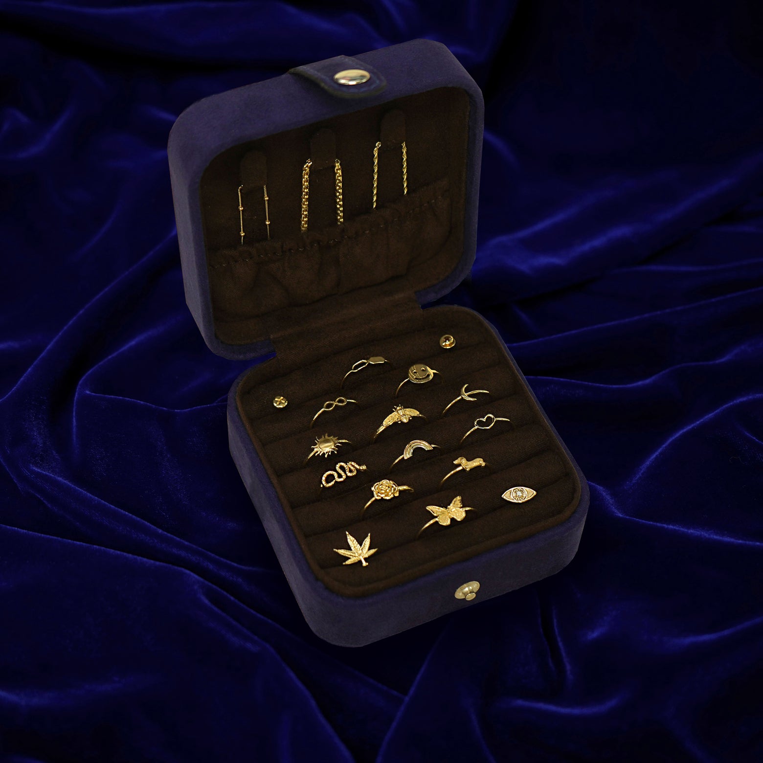 An open Automic Gold Travel Case  with multiple pieces of solid gold jewelry inside and chains tucked into the pouch on top