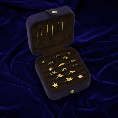 An open Automic Gold Travel Case  with multiple pieces of solid gold jewelry inside and chains tucked into the pouch on top