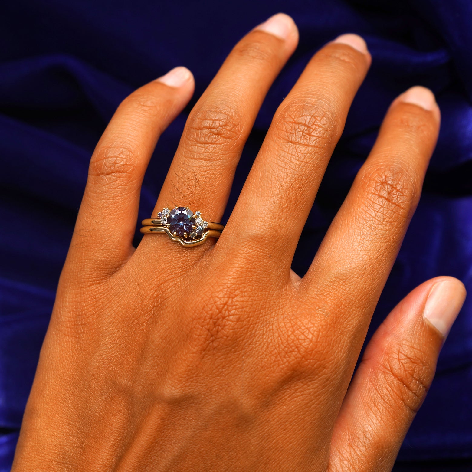 Close up view of a model's hand wearing a yellow gold Alexandrite Cluster Ring Set