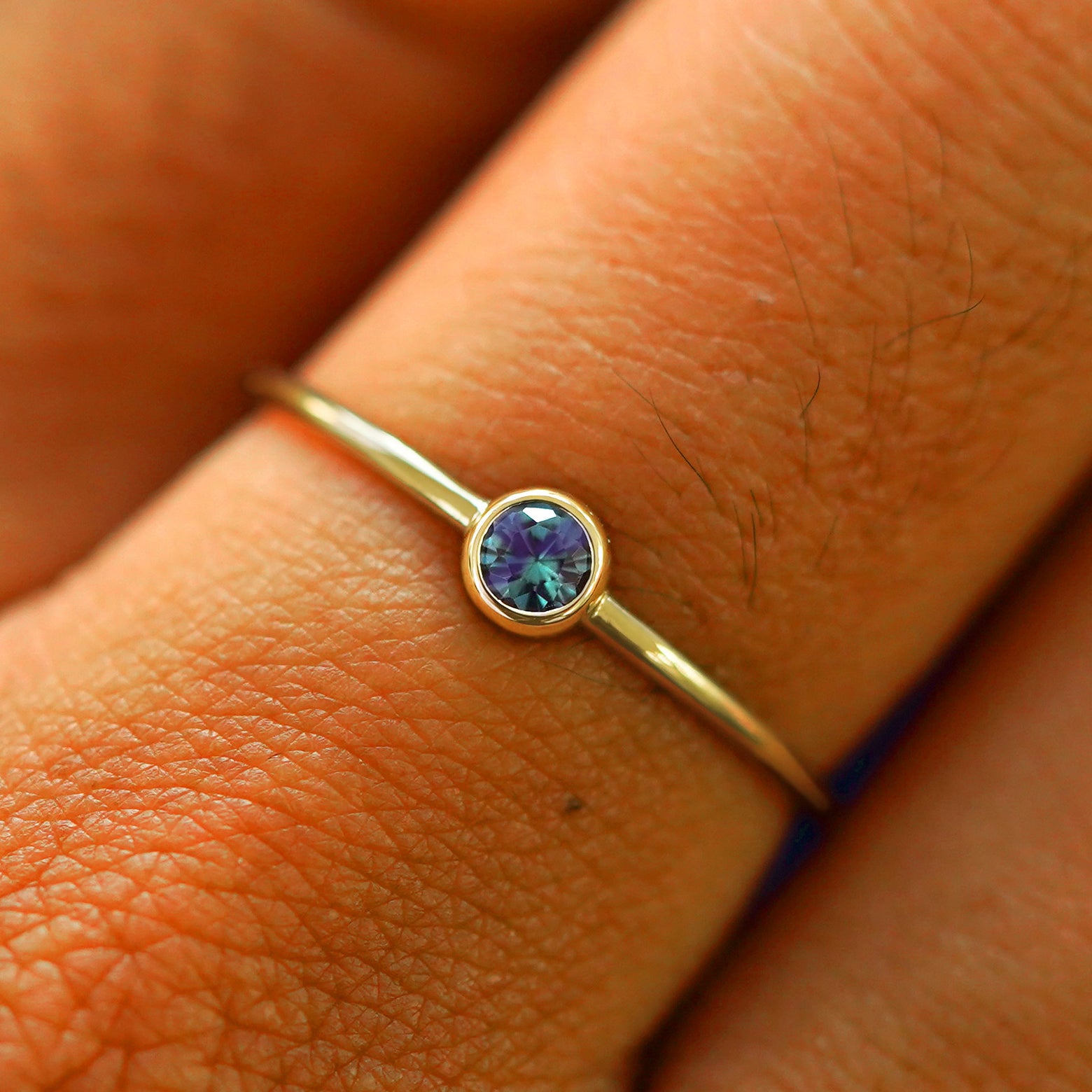 Close up view of a model's fingers wearing a 14k yellow gold Alexandrite Ring