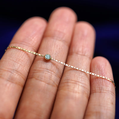 A yellow gold Aquamarine Bracelet resting on a model's fingers