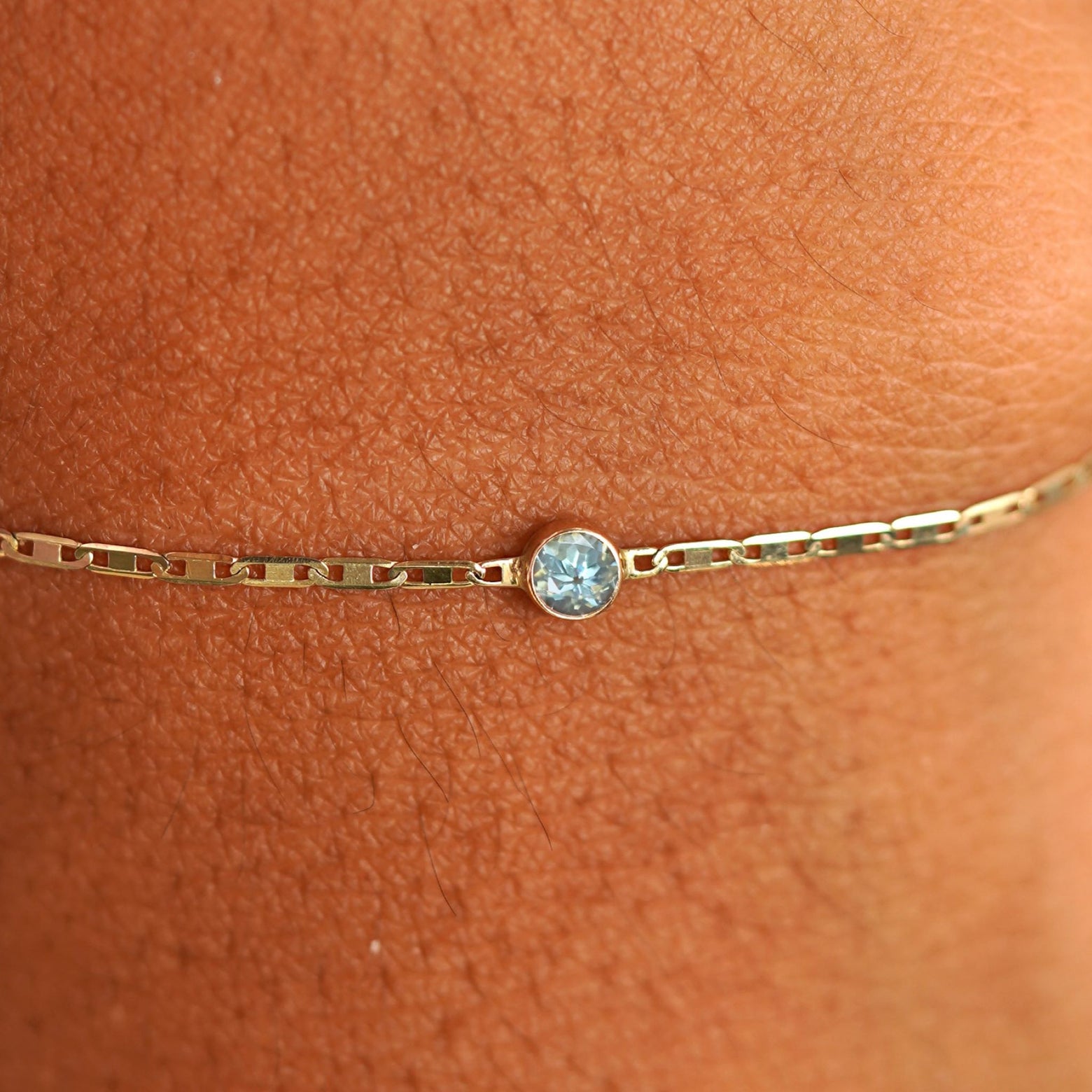 Close up view of a models wrist wearing 14k yellow gold Aquamarine Bracelet