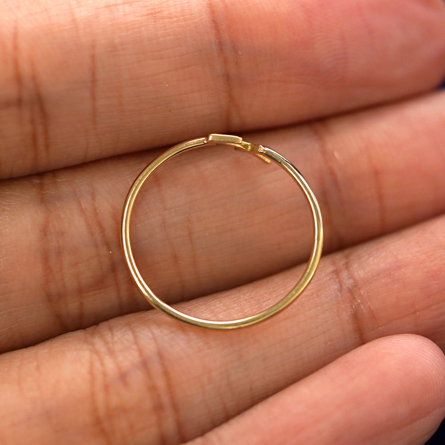 A yellow gold Sagittarius Horoscope Ring in a model's hand showing the thickness of the band