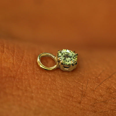A solid yellow gold Peridot Charm for earring resting on the back of a model's hand