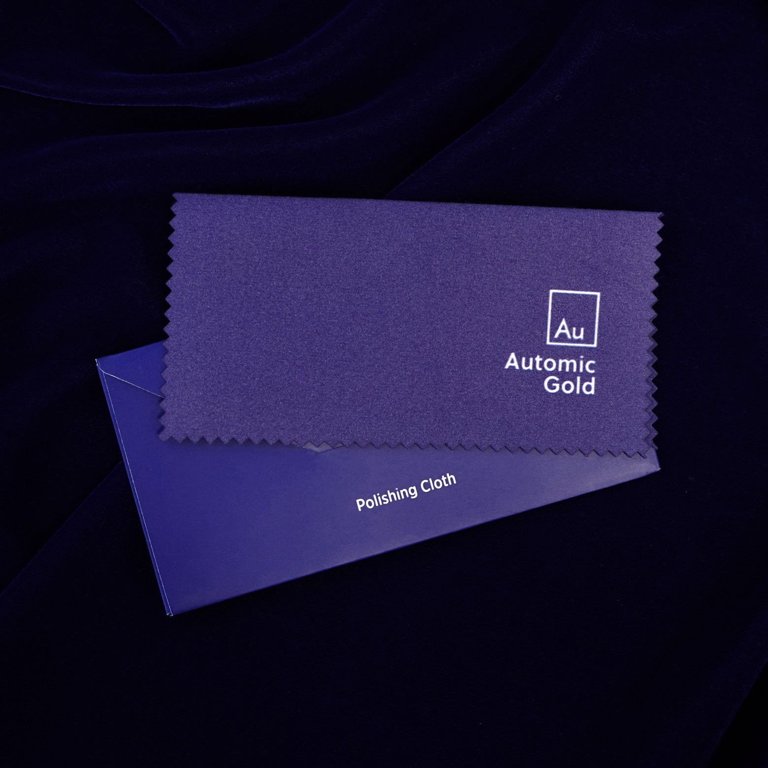 An Automic Gold jewelry polishing cloth laying on top of a blue envelope