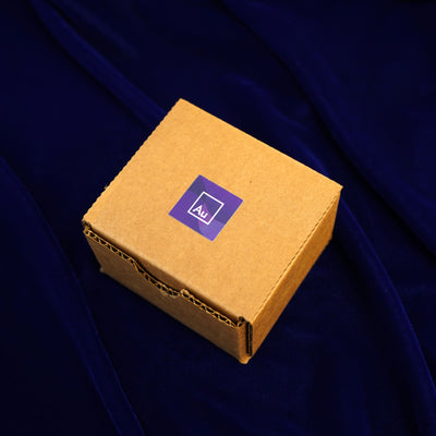 A closed Automic Gold Minimal Packaging box on a dark blue background