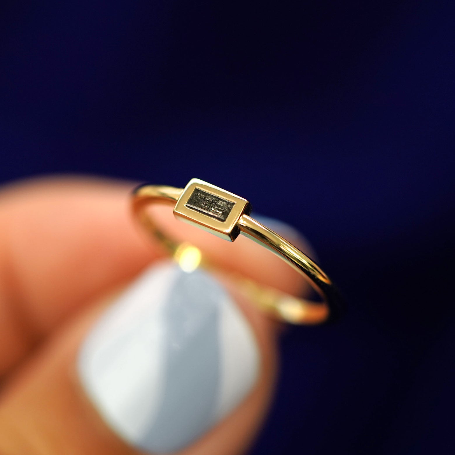 A model holding a Baguette Salt and Pepper Diamond Ring tilted to show the details of the thick bezel setting