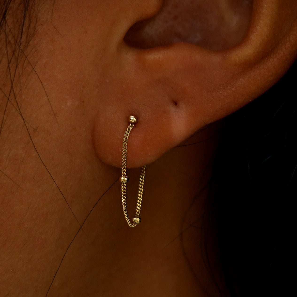 "Close up view of a model's ear wearing a yellow gold Beaded Chain Loop Earring "