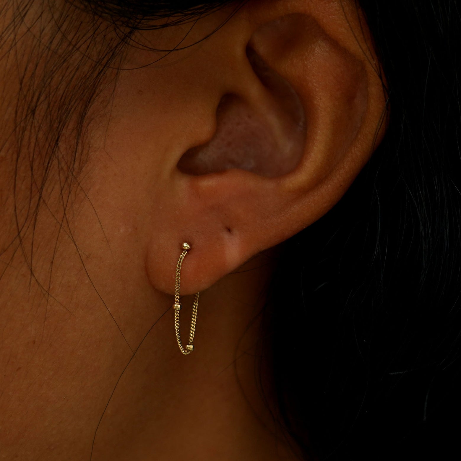 A model's ear wearing a solid yellow gold Beaded Chain Loop Earring