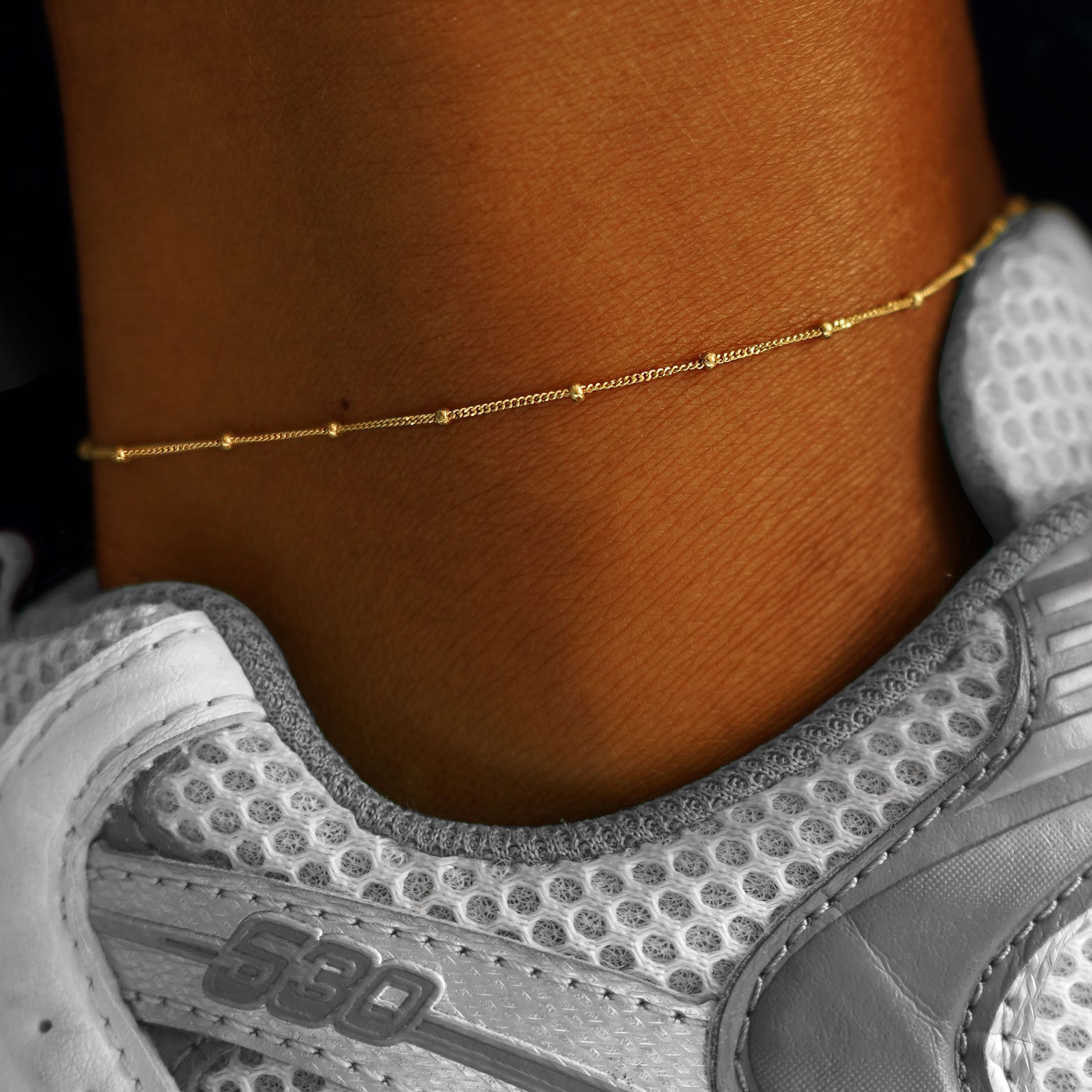 A model's ankle wearing a yellow gold Beads Anklet