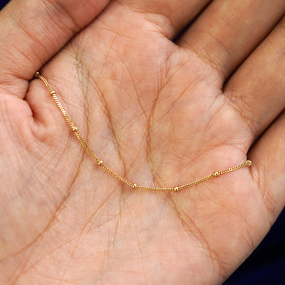 A yellow gold Beaded Essential Hand Bracelet draped on a model's palm