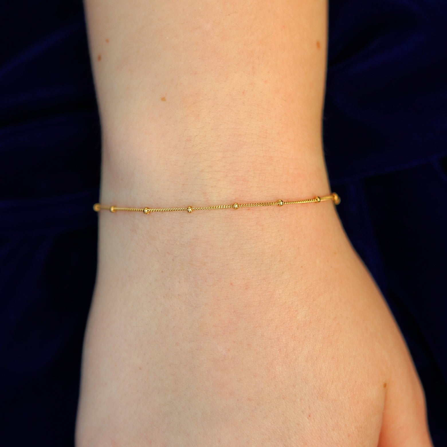 A model's wrist wearing a 14k solid gold Beaded Essential Bracelet