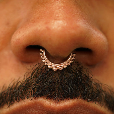 Close up view of a model's nose wearing a 14k rose gold Beaded Septum