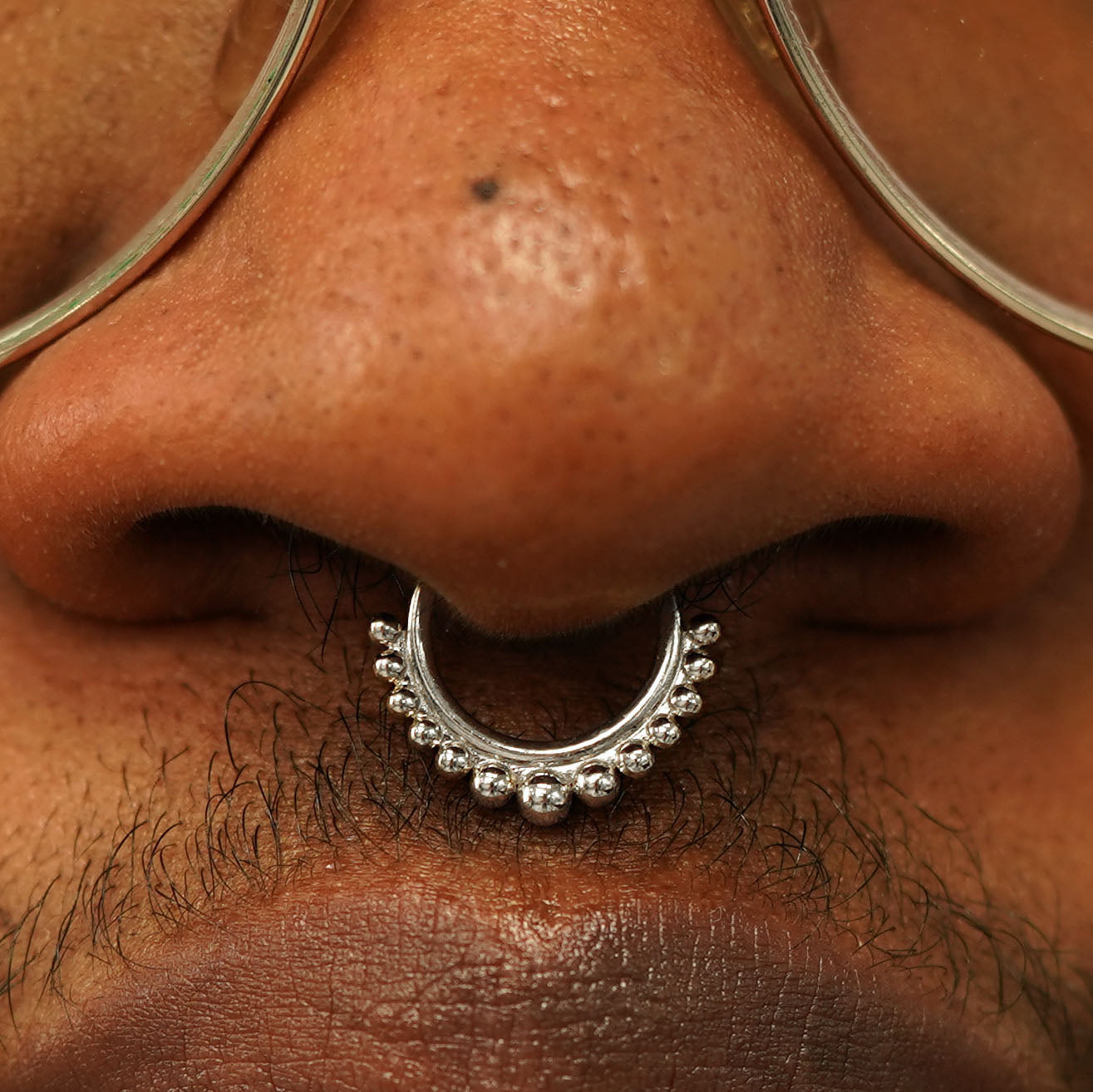 Close up view of a model's nose wearing a 14k white gold Beaded Septum